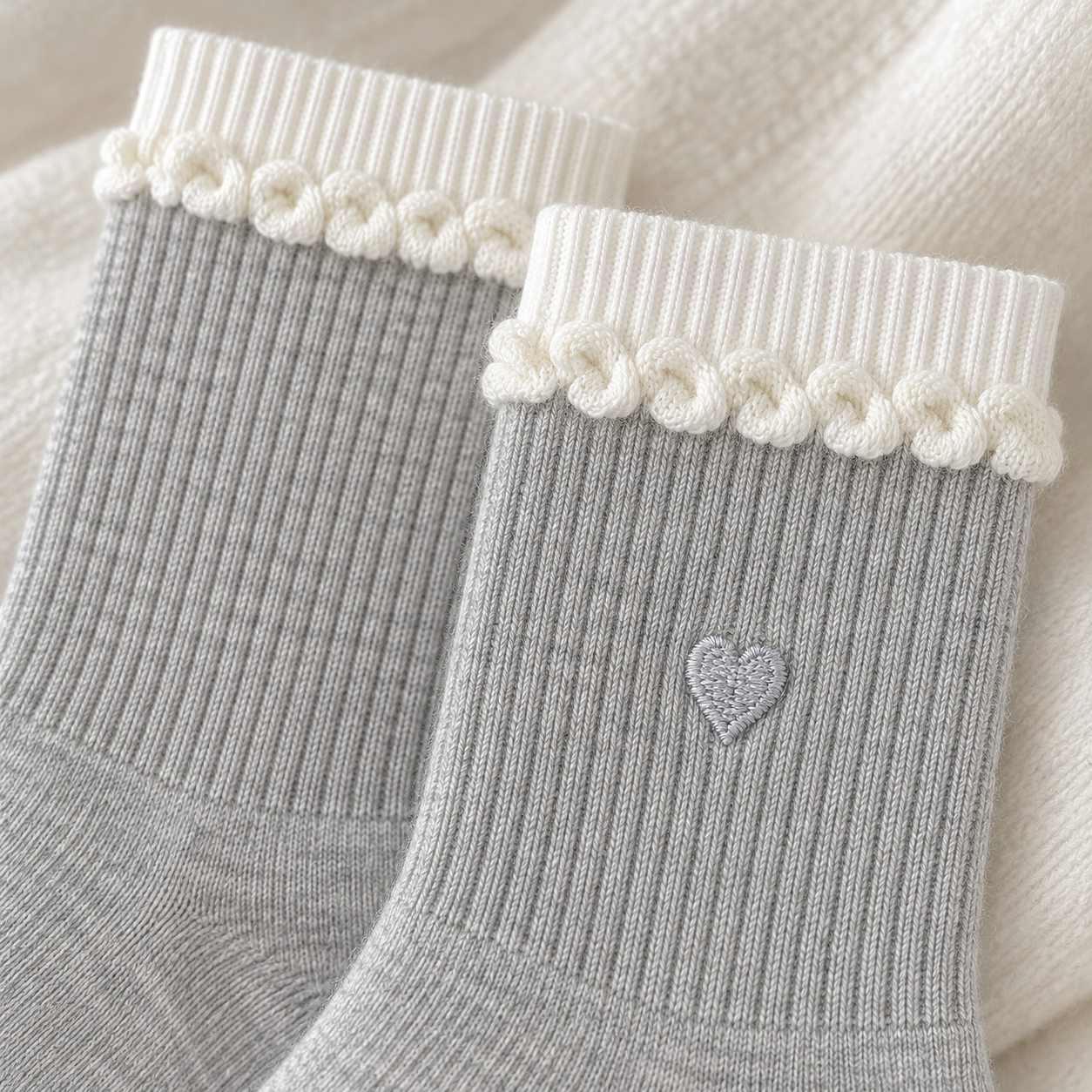 AI close product illustration of the white ribbed upper bands, curled-knit row and pale-gray heart on Light Gray socks.