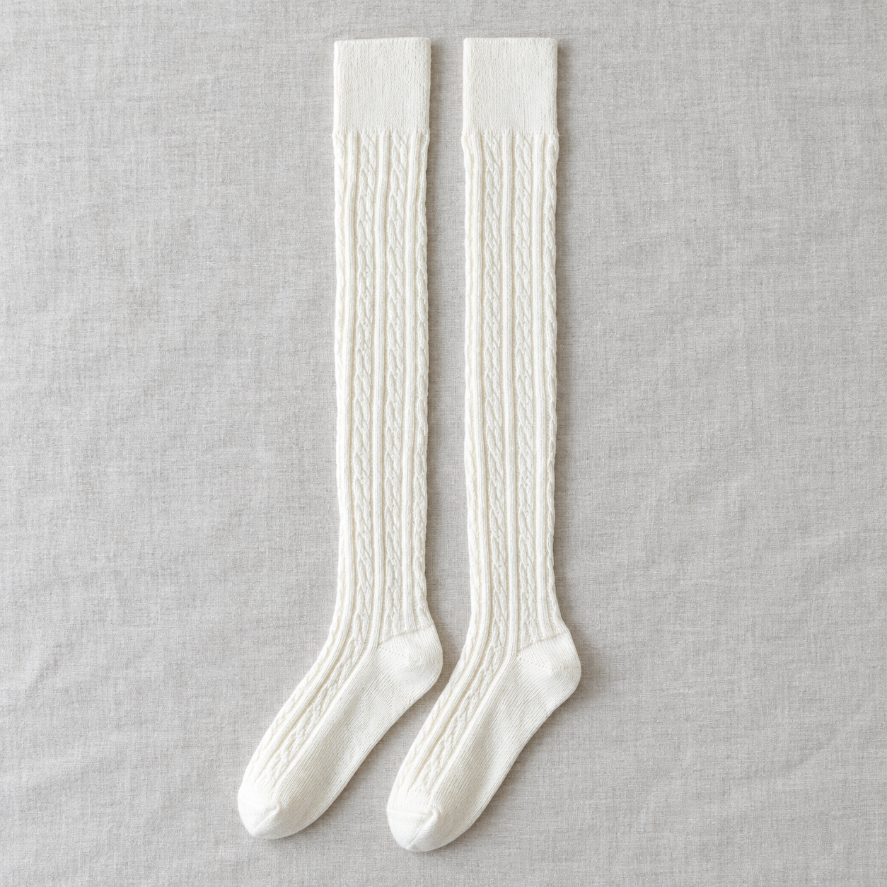 AI product illustration of a Cream long-sock pair on gray linen, showing narrow cable columns, plain straight cuffs and shaped feet.