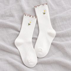 AI product illustration of an empty White matching ribbed pair with stemmed daisy embroidery and narrow brown wavy edges on gray linen.