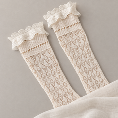 AI product illustration of two Cream diamond-trellis sock shafts on gray paper, with lace cuffs and lower foot ends concealed by fabric.