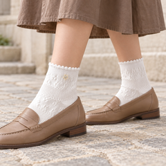 AI styling illustration of White daisy textured socks with tan loafers and a brown skirt during a supported step in a stone courtyard.
