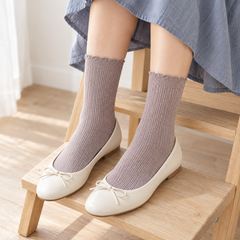 AI styling illustration of Heather Taupe fine-rib socks with cream flats, shown from above on pale wooden steps beneath a blue-gray skirt.