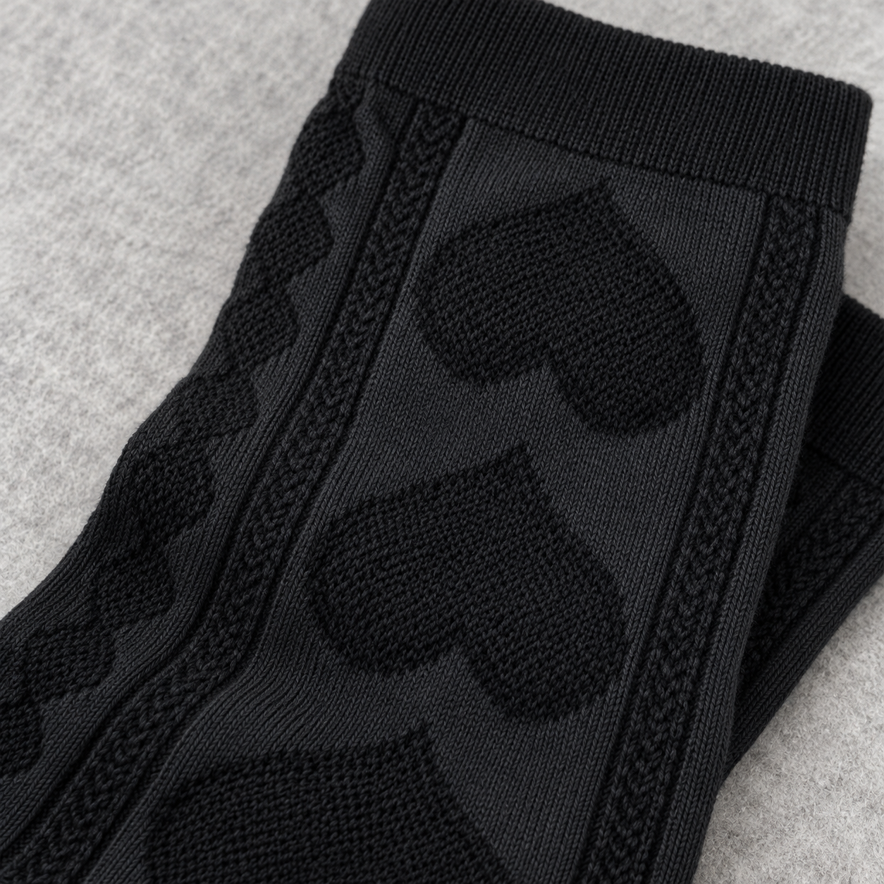 AI detail illustration of the large tonal heart-knit panels and narrow chain columns on Black socks.