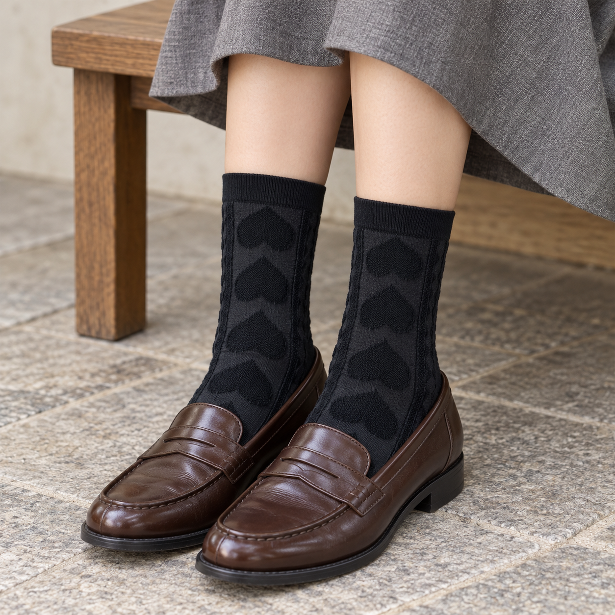AI styling illustration of Black raised-heart socks with brown loafers and a gray skirt on a wood bench.