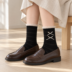 AI seated styling illustration of Black striped-knit tulle-cuff socks with brown loafers and an oat skirt beside a wood bench.