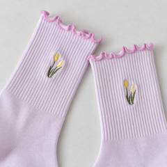 AI product detail illustration of Lavender fine-rib sock shafts with two yellow tulip heads and pink-purple wavy edges on gray paper.