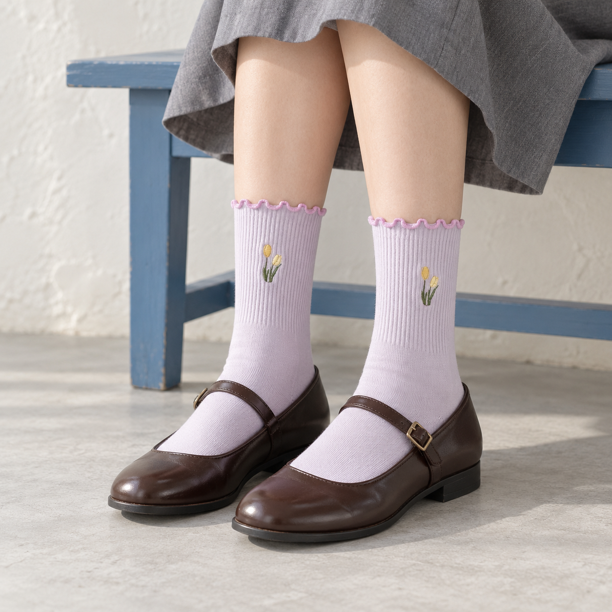 AI seated styling illustration of Lavender tulip socks with brown Mary Janes beside a muted blue bench.