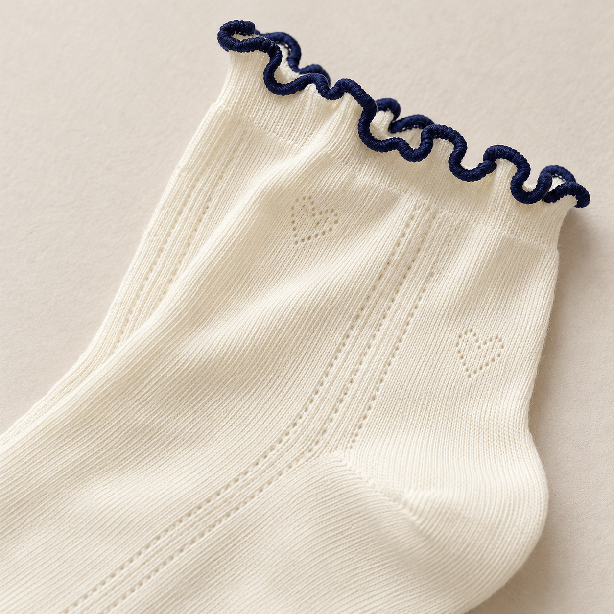 AI detail illustration of a Cream sock opening with thin navy wavy edging and subtle heart pointelle.