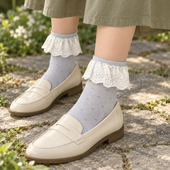 AI garden styling illustration of Light Blue eyelet socks with White embroidered flounces, cream loafers and an olive skirt.