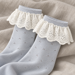 AI product detail illustration of Light Blue sock shafts and White embroidered scalloped flounces on gray linen.
