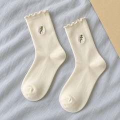AI product illustration of a Lettuce-Edge White sock pair with small pink floral sprigs and matching wavy cuffs on gray-blue cotton.