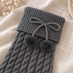 AI detail illustration of a Dark Gray folded ribbed leg warmer cuff, gray cord bow and two yarn pompom ends.