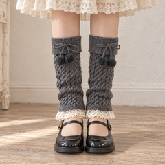 AI front styling illustration of Dark Gray footless cable-knit pompom leg warmers with black Mary Janes and a cream skirt.