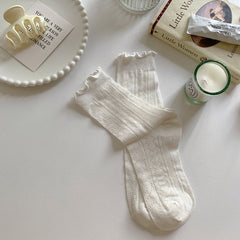 White socks with vertical leaf-like openwork and lightly ruffled cuffs, displayed as a pair