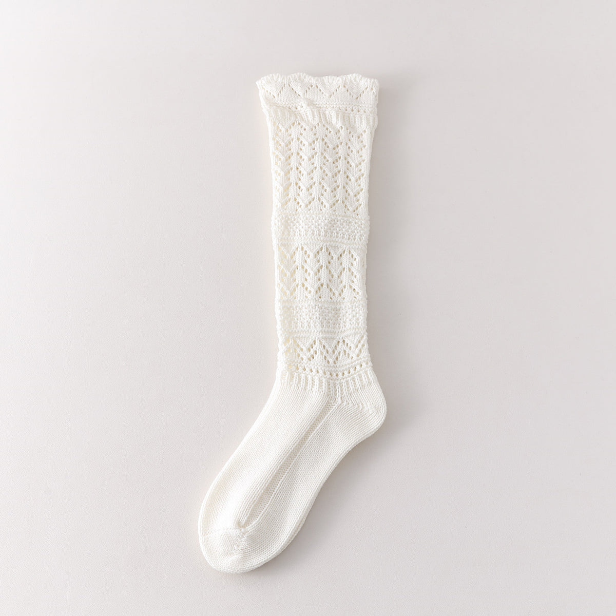 White long sock with three leaf pointelle sections, two broad textured bands and a geometric knit cuff