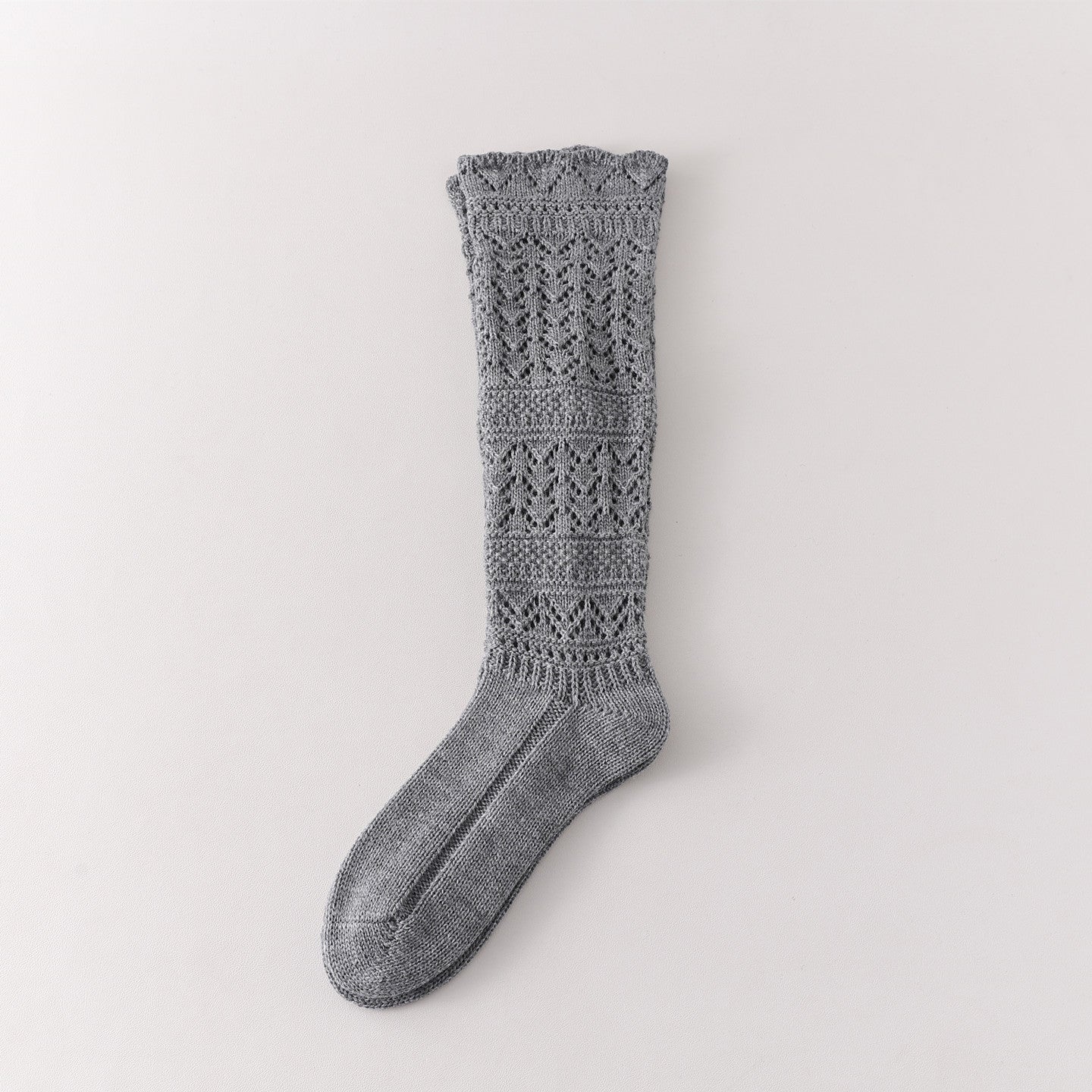 Gray long sock showing leaf-shaped openwork, broad textured knit bands and a patterned cuff