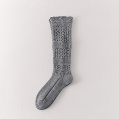 Gray long sock showing leaf-shaped openwork, broad textured knit bands and a patterned cuff