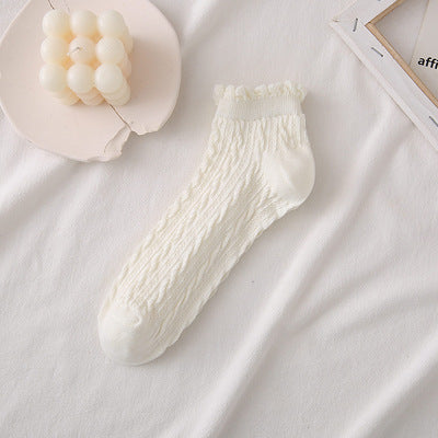 Untouched supplier reference showing one Milk White short cable sock with a curled cuff, narrow band and plain toe and heel areas.