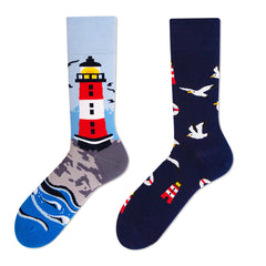 Coordinated mismatched crew sock pair with a red-and-white lighthouse scene and navy seagull pattern