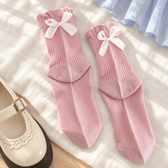 AI styling illustration of one Pink sock pair with broad white bows, fine upper grids and long vertical eyelet bands laid on ivory linen