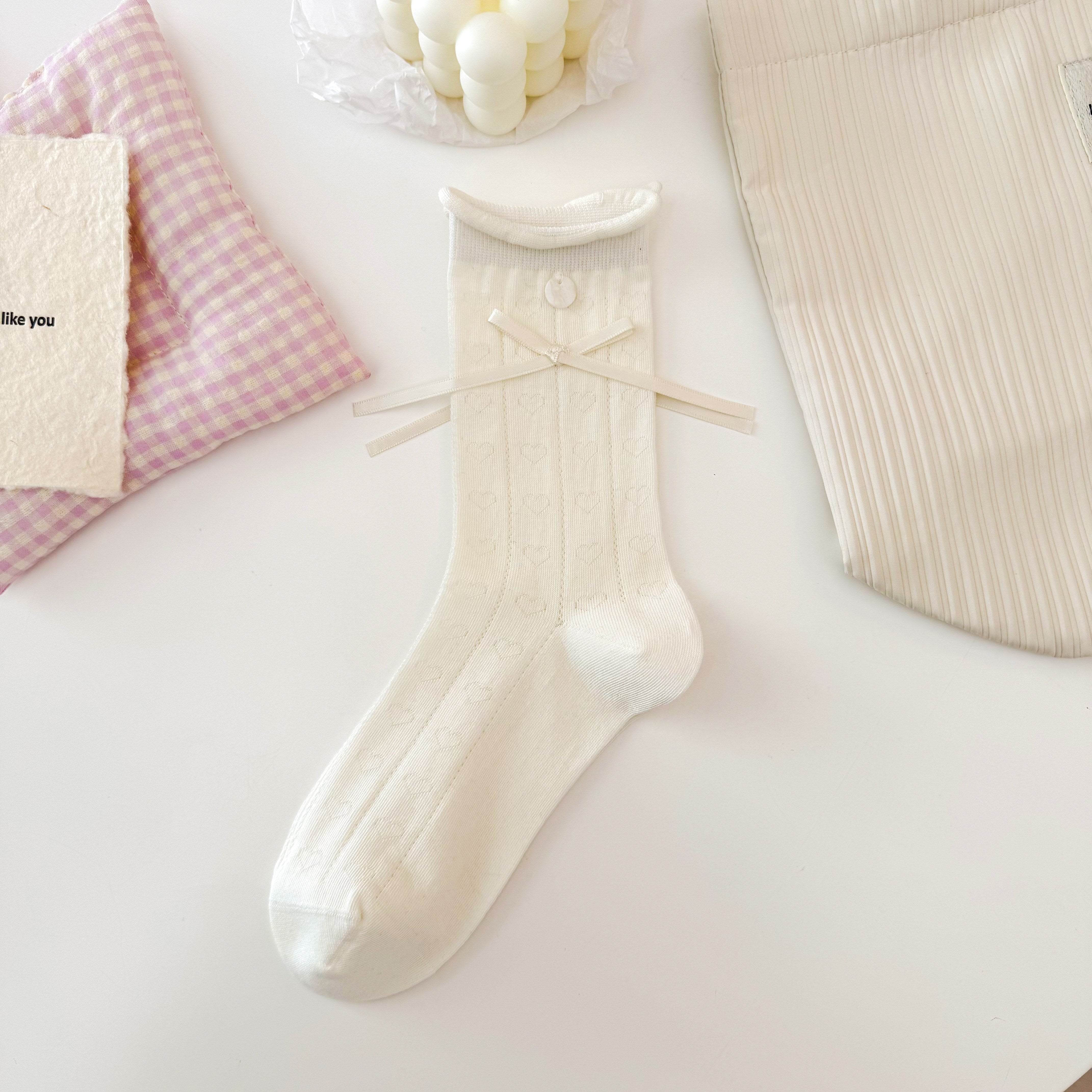 Cream Heart pattern crew sock with rows of knitted hearts, a rolled cuff, round button and long ribbon bow.