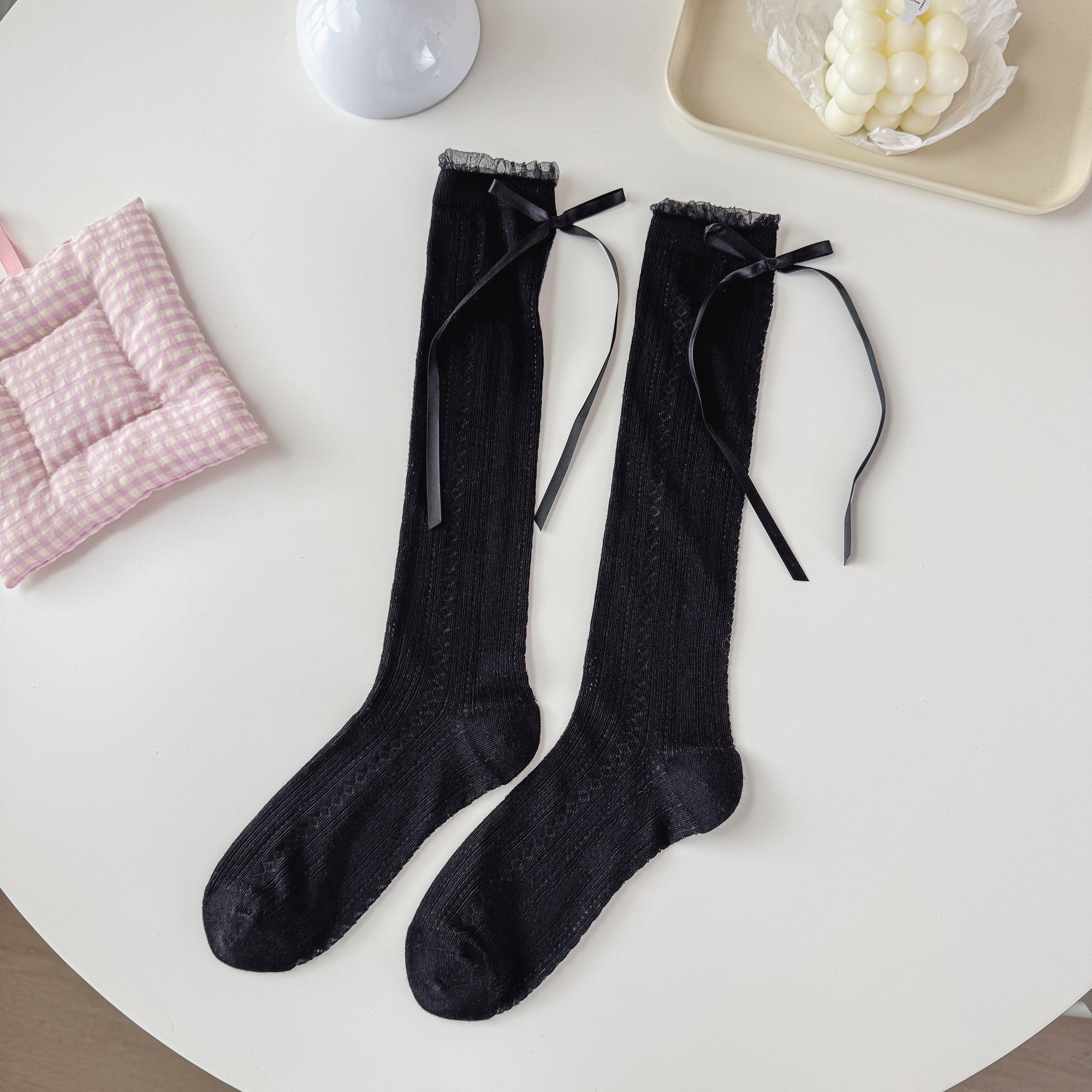 Black pointelle crew socks with a narrow sheer cuff rim and long black ribbon bows