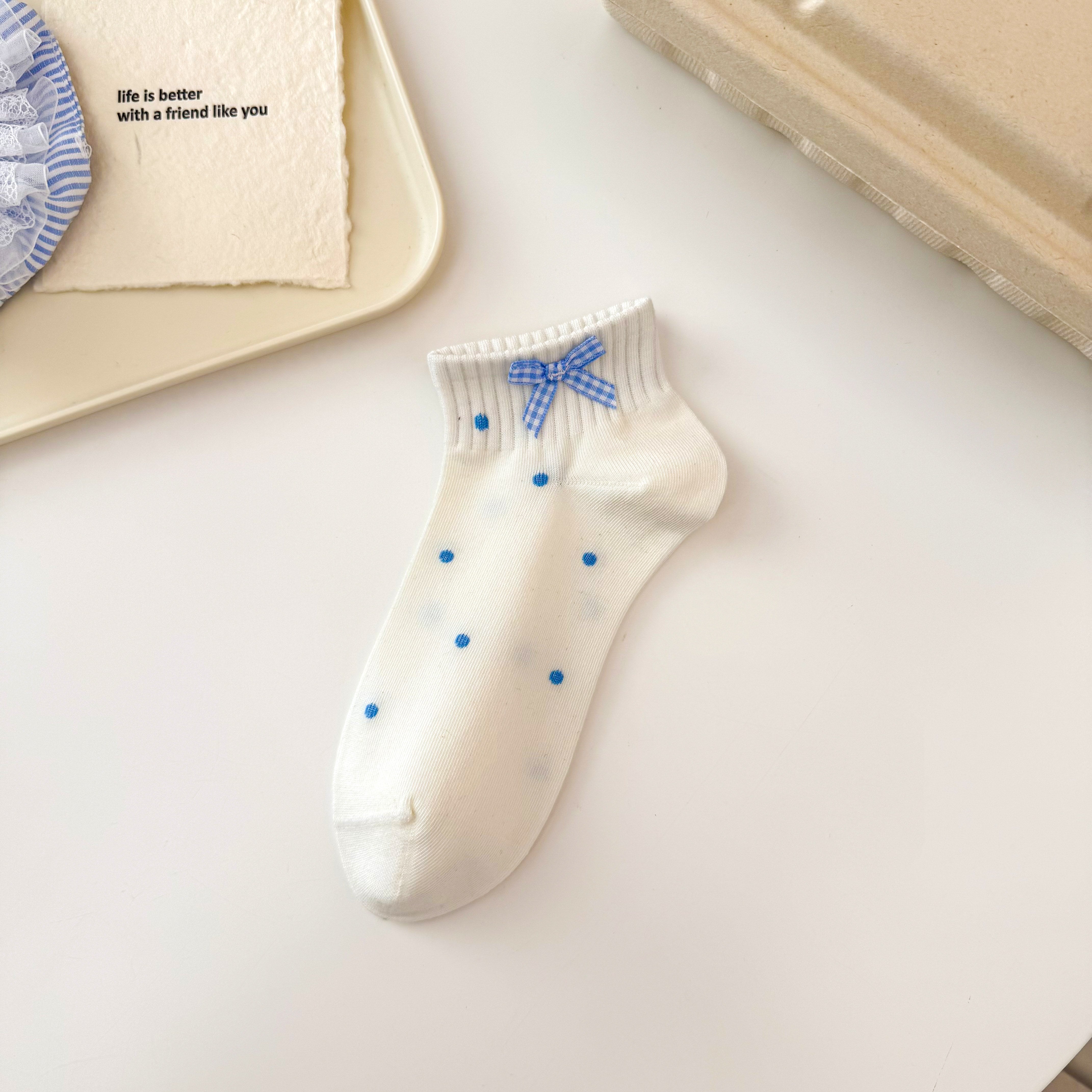 Blue Dot style ivory ankle sock with sparse blue dots, a ribbed cuff and gingham bow.