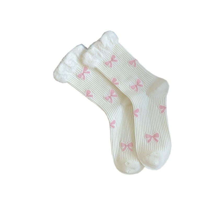 White ribbed crew socks laid flat with pink bow motifs and fluffy cuff edges