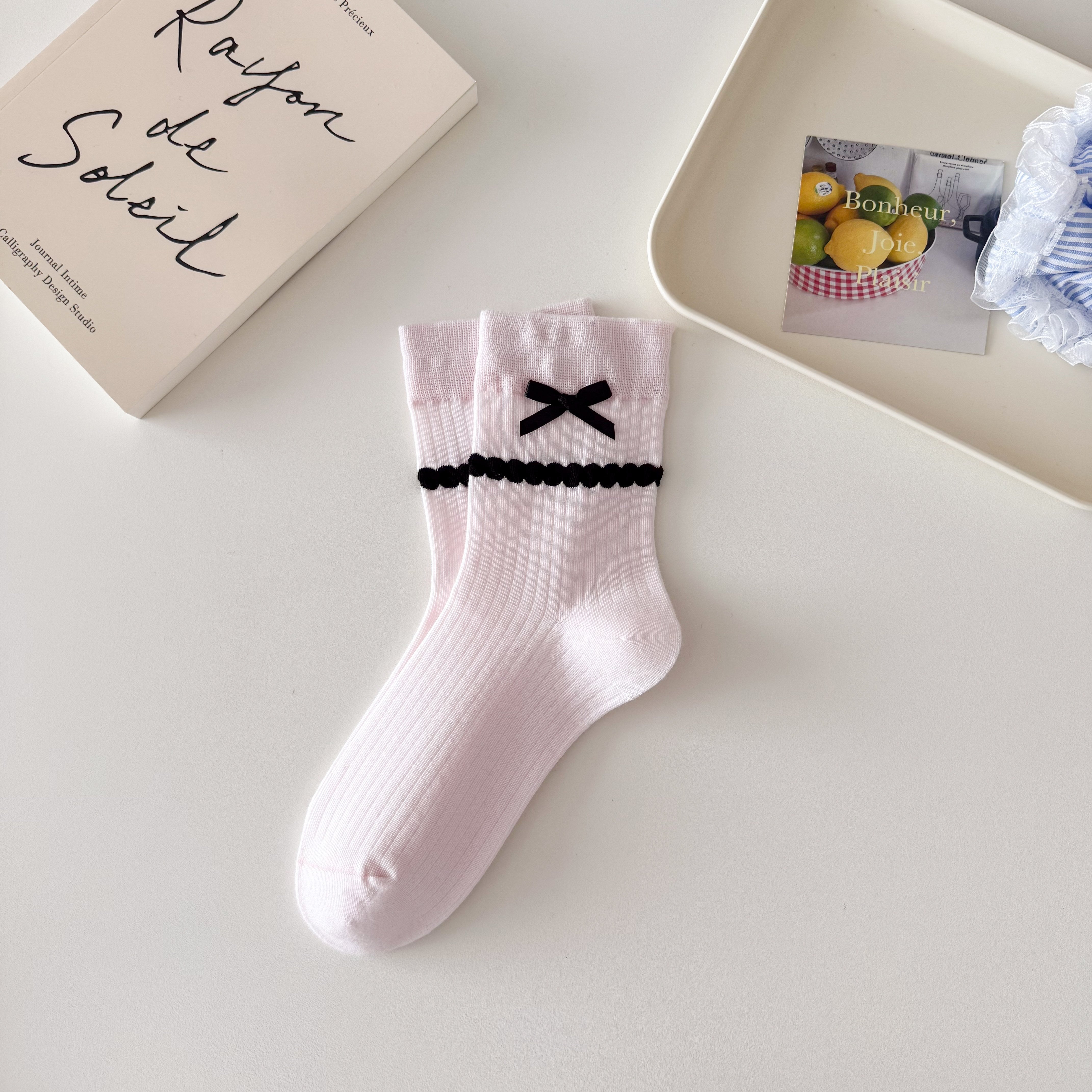 Pink ribbed crew socks with straight cuffs, black ribbon bows and raised black dot knit bands.