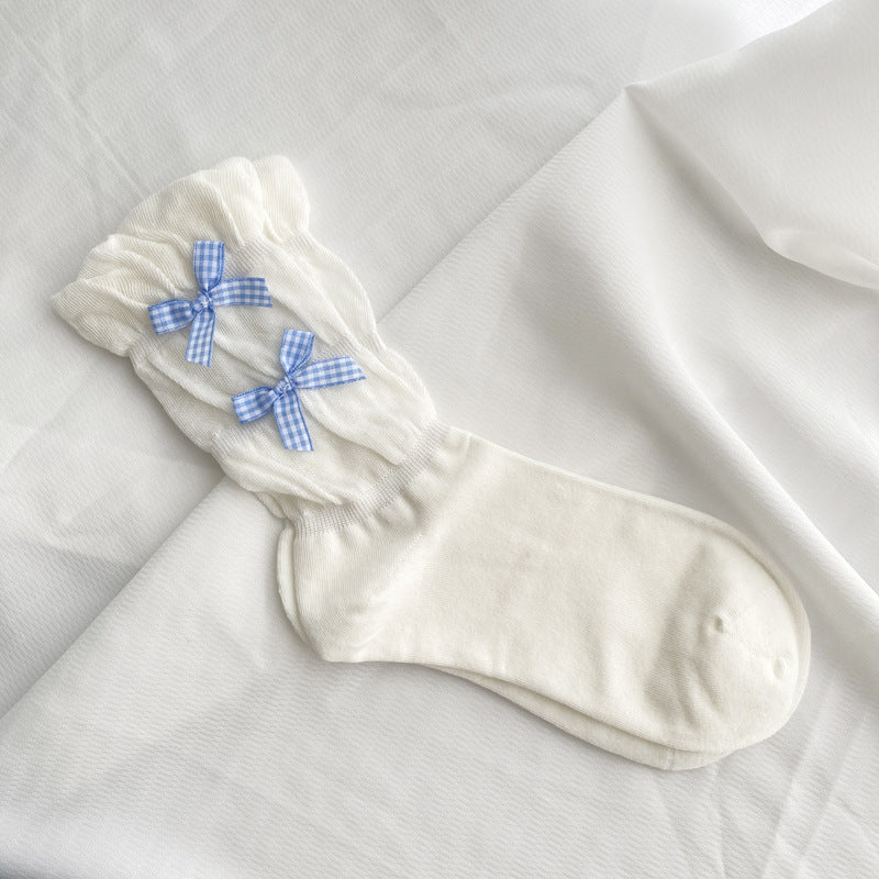 White knitted sock with two blue gingham bows arranged vertically over diagonal ruching