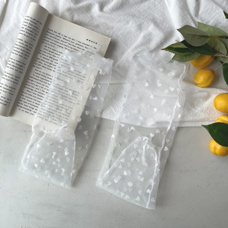 Pair of White sheer crew-style socks with scattered small hearts and fine wavy cuff edges