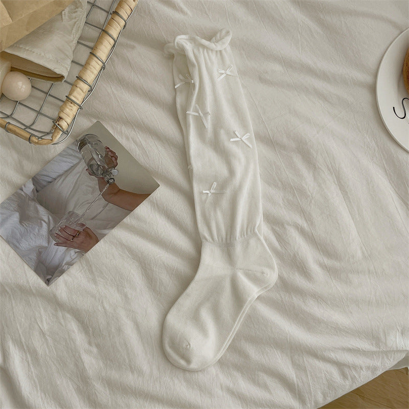 Original supplier photo of a white long sock with scattered small ribbon bows and a rolled cuff; retail quantity is one pair